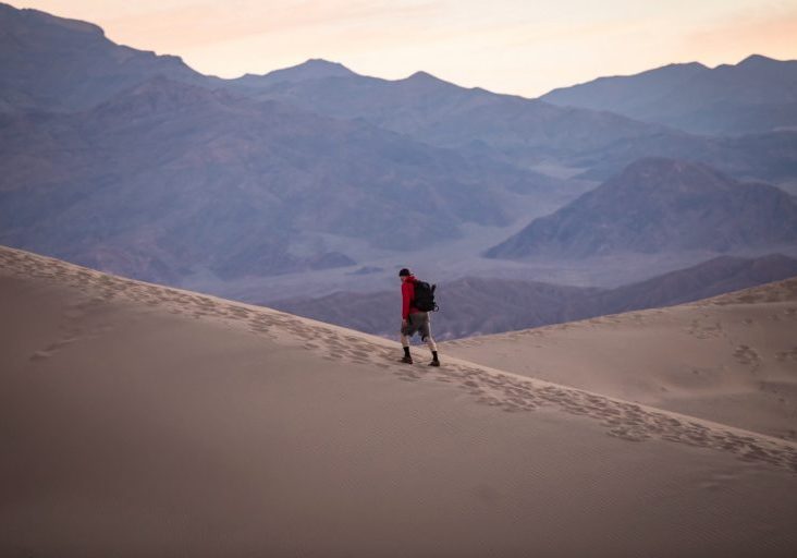 person in red hoodie walking on desert